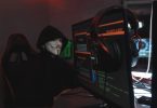 person in black hoodie hacking a computer system